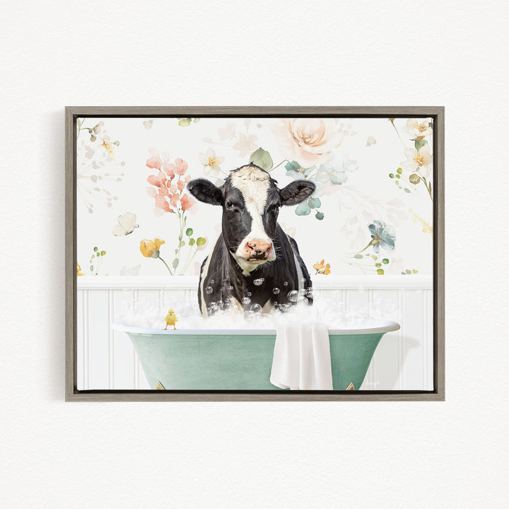 A black and white cow is sitting in a green bathtub filled with bubbles, surrounded by a floral wallpaper.