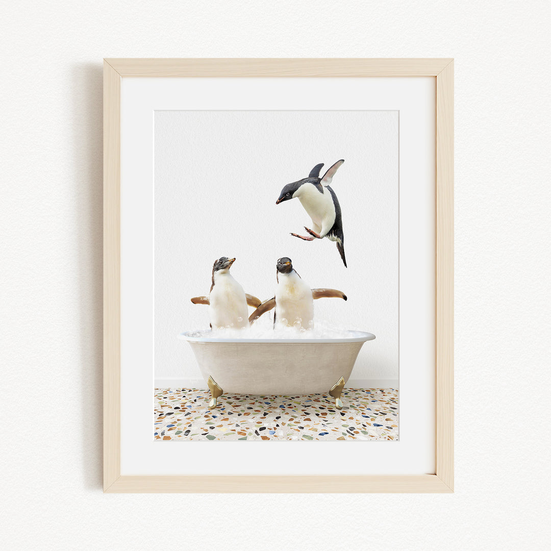 A framed image depicting two penguins sitting in a bathtub, with one penguin flying towards the other.