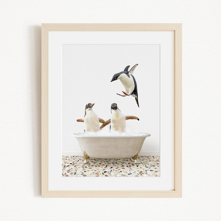 A framed image depicting two penguins sitting in a bathtub, with one penguin flying towards the other.