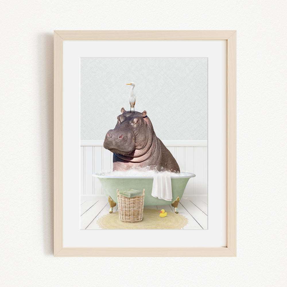 A framed image depicting a hippopotamus sitting in a bathtub, with a bird perched on its head.