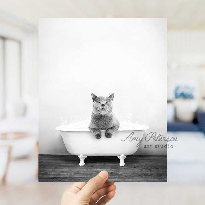 a person holding up a picture of a cat in a bathtub