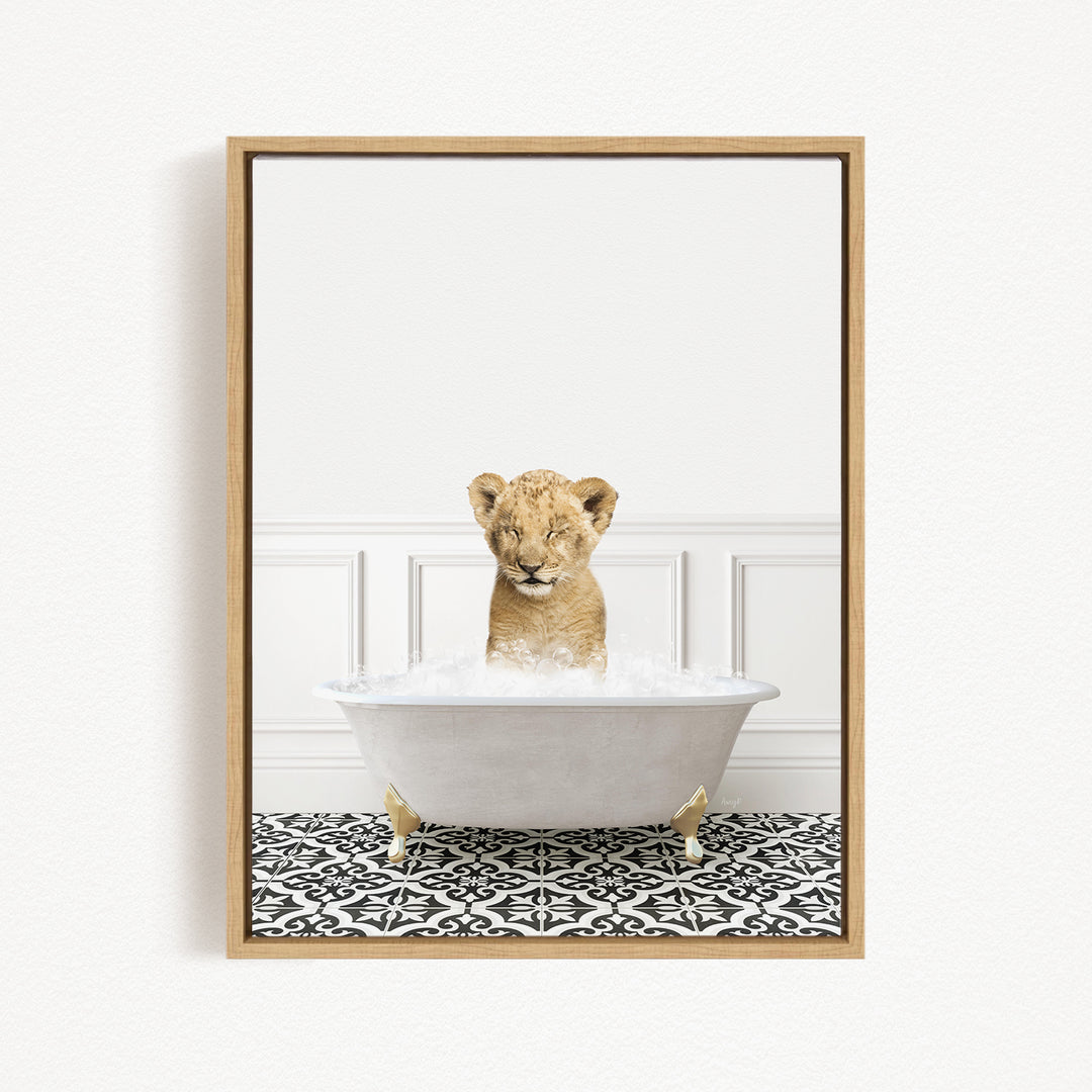 A young lion cub sitting in a white bathtub filled with water, looking up at the camera.