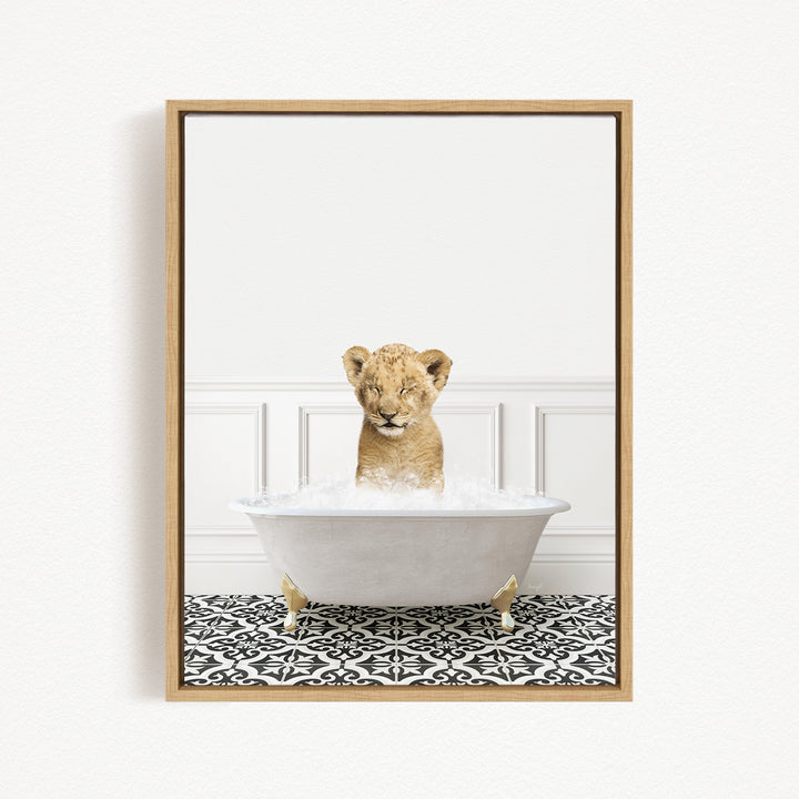 A young lion cub sitting in a white bathtub filled with water, looking up at the camera.