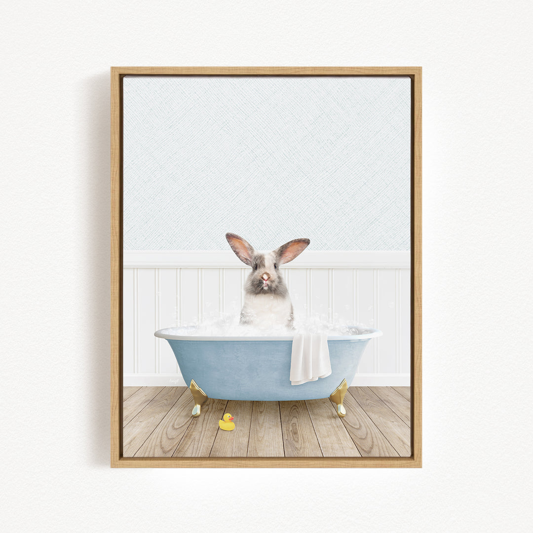 A gray and white rabbit sitting in a blue bathtub filled with water, with a yellow rubber duck nearby.