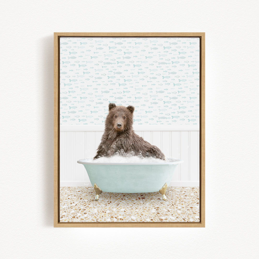 A brown bear sitting in a light blue bathtub filled with bubbles, with a patterned wall behind it.