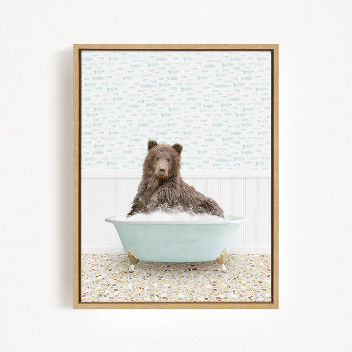 A brown bear sitting in a light blue bathtub filled with bubbles, with a patterned wall behind it.