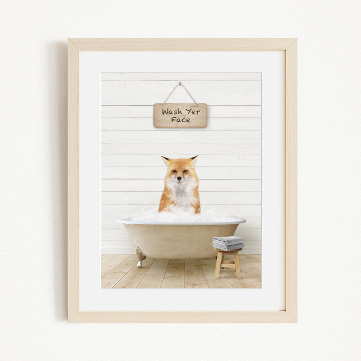 A framed image of a fox sitting in a bathtub, with a sign above that says "Wash Your Face".