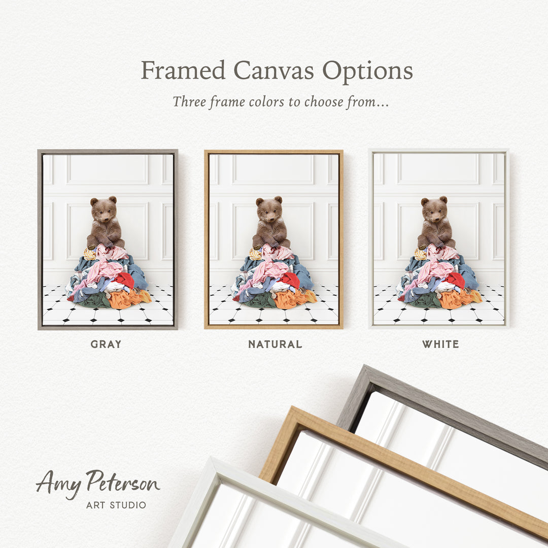 three framed canvas options, each featuring a teddy bear sitting on a pile of clothes. The options include a gray frame, a natural frame, and a white frame.