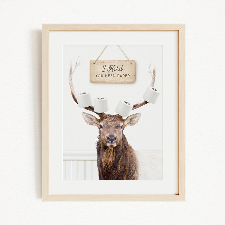 A framed image of a deer with antlers, displaying a sign that says "I herd you need paper".