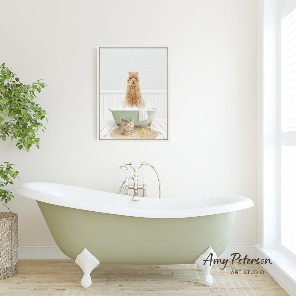 A framed image of a dog sitting in a bathtub is displayed on the wall above a green clawfoot bathtub in a bright, white-walled bathroom.