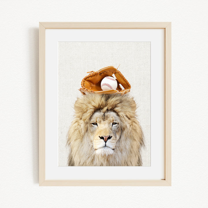 A framed image of a lion wearing a baseball glove on its head, with a baseball resting on top of the glove.