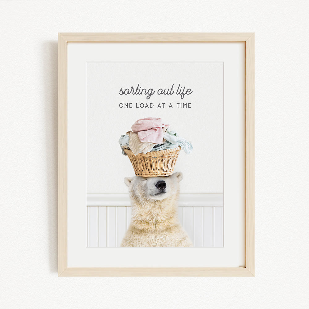 A polar bear balancing a basket of laundry on its head, with the text "sorting out life" above the basket.