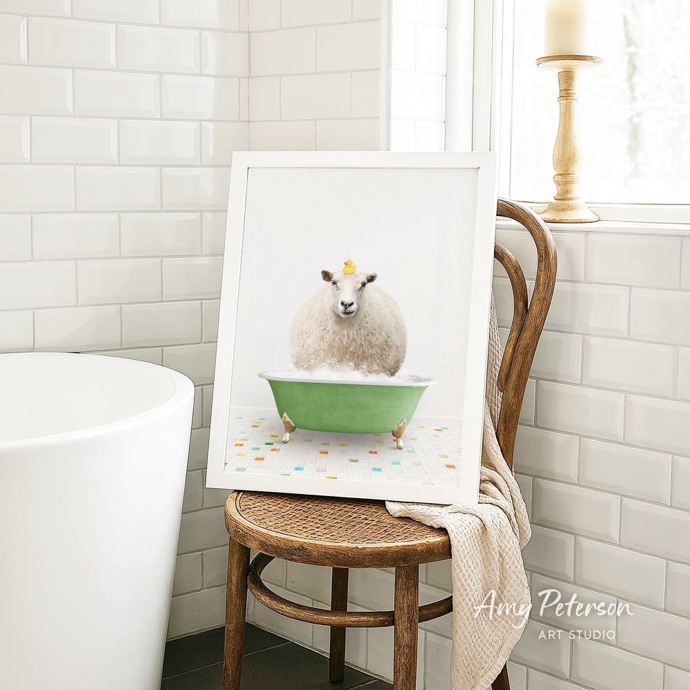 A framed image of a sheep sitting in a green bathtub, surrounded by colorful tiles, is displayed on a wooden chair in a bathroom setting.