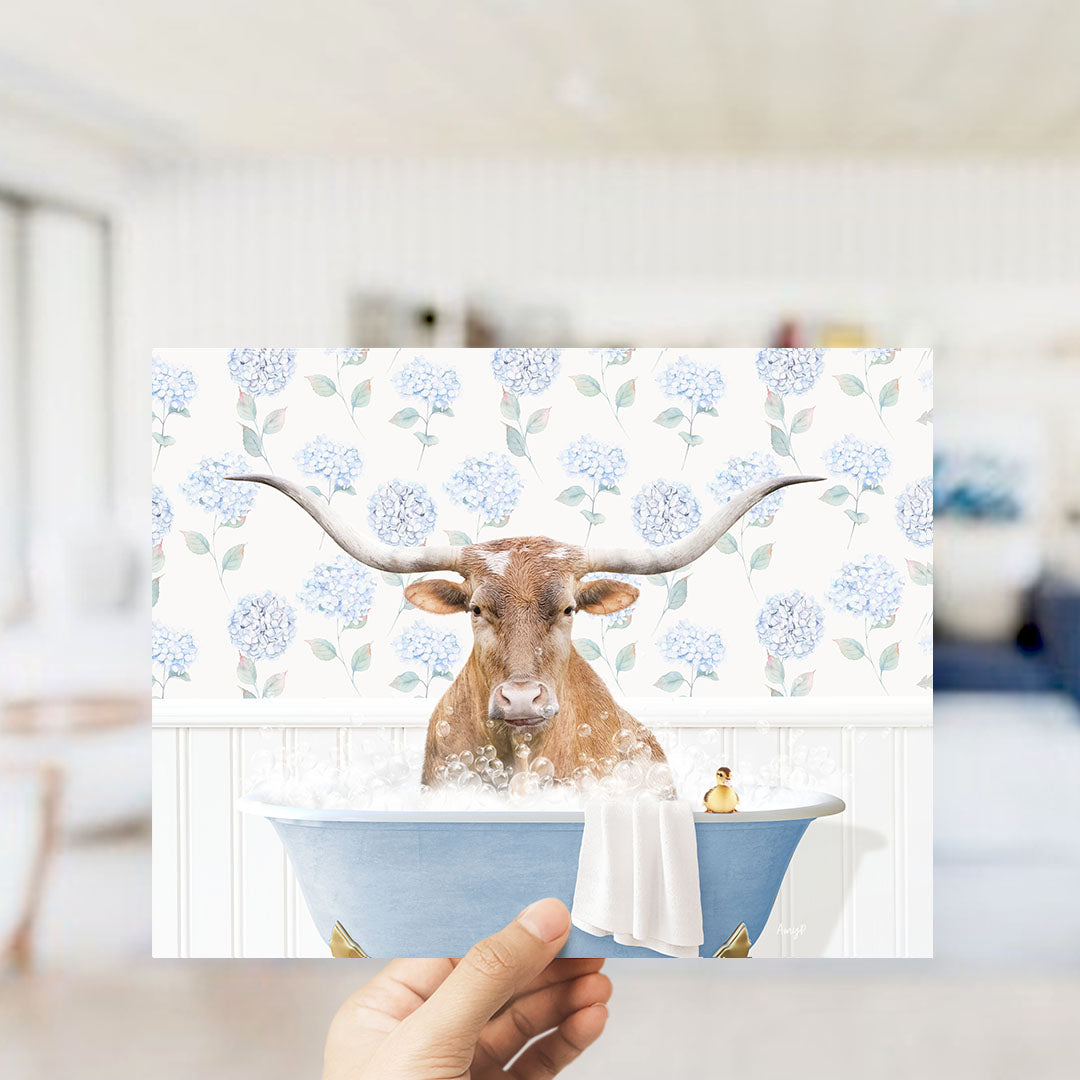 A brown cow with large horns is sitting in a blue bathtub filled with water, surrounded by a floral pattern.