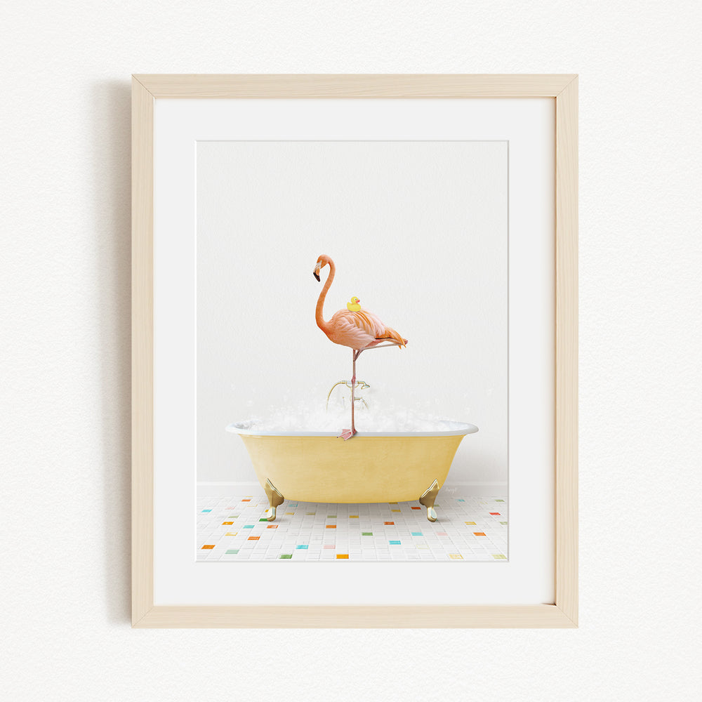 A framed image depicting a pink flamingo standing on a yellow bathtub filled with water, surrounded by colorful tiles on the floor.