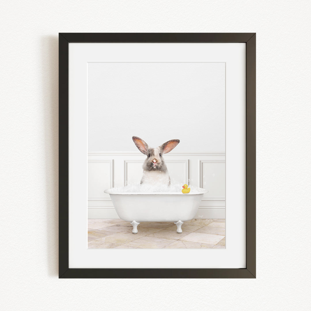 A white rabbit sitting in a white bathtub, with a yellow rubber duck floating in the water.