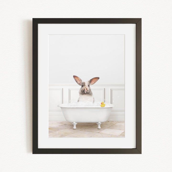 A white rabbit sitting in a white bathtub, with a yellow rubber duck floating in the water.