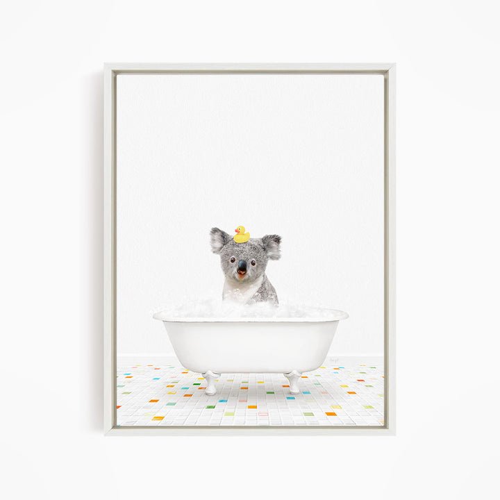 A koala bear sitting in a white bathtub filled with bubbles, with a rubber duck perched on its head.