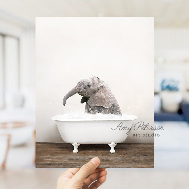 a person holding up a picture of an elephant in a bathtub