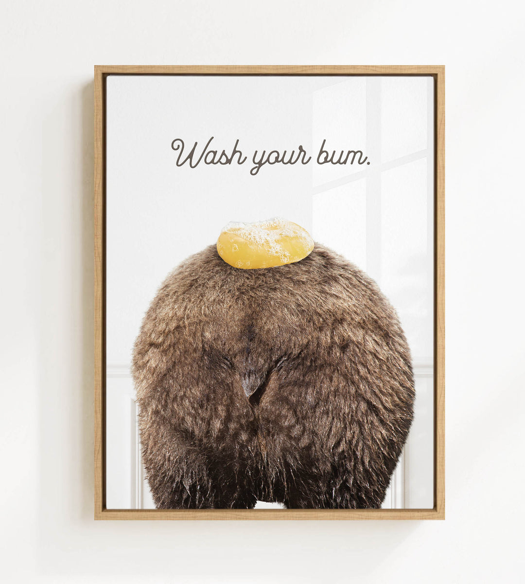a close-up of a furry brown bear with a yellow object on its head, accompanied by the text "Wash your butt."