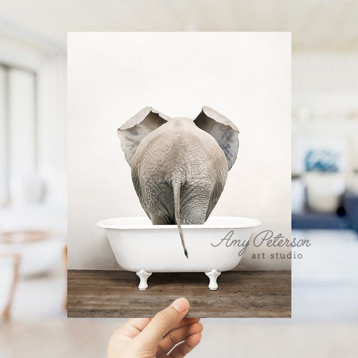 a person holding up a picture of an elephant in a bathtub