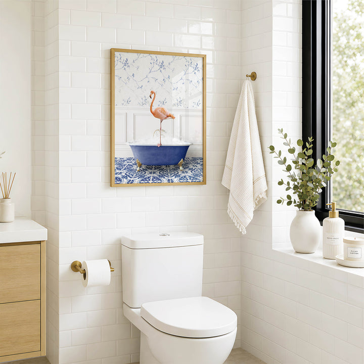 a bathroom with a white toilet, a framed picture of a pink flamingo in a blue bathtub, and a window with greenery on the sill.