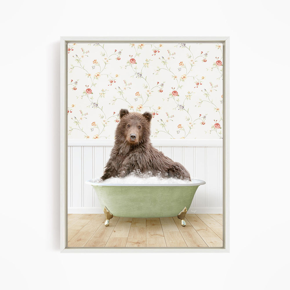 A brown bear sitting in a green bathtub filled with bubbles, with a floral wallpaper in the background.