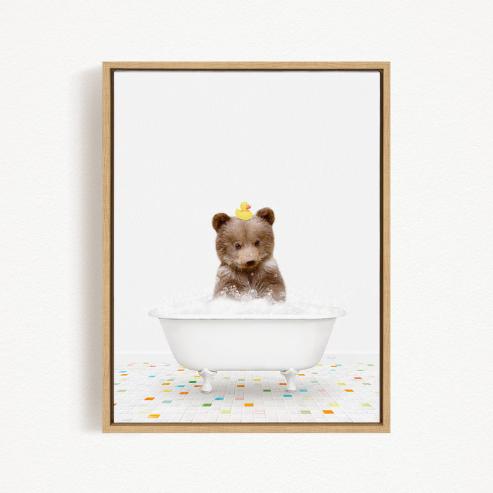 A cute brown bear sitting in a white bathtub filled with bubbles, with a yellow rubber duck on its head.