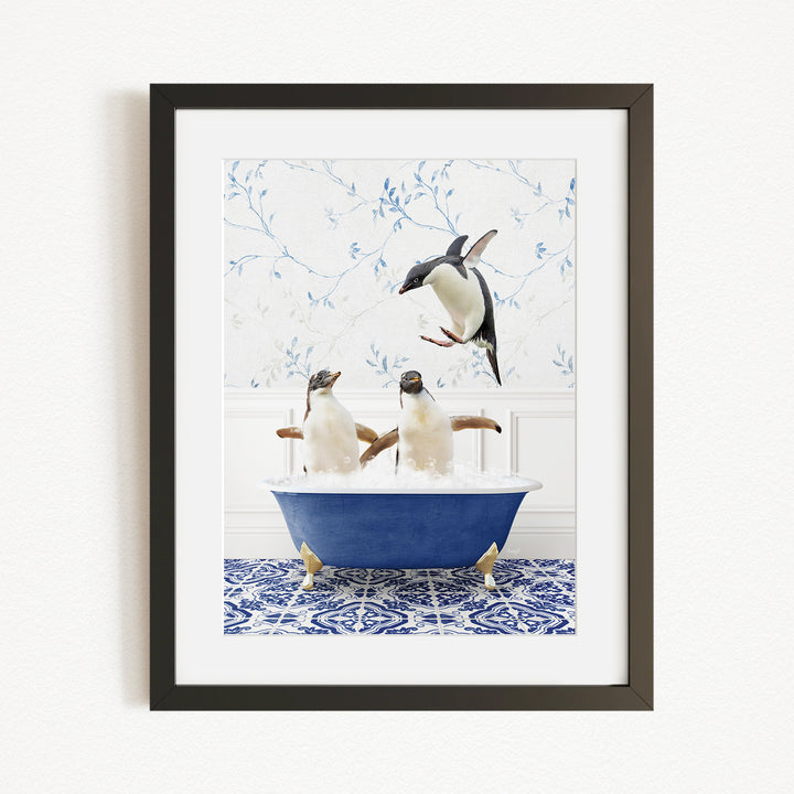 A framed image depicting two penguins sitting in a blue bathtub, with one penguin flying towards the other.
