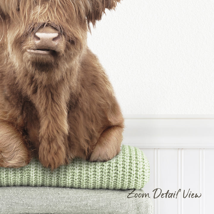 A close-up image of a brown furry animal, possibly a dog or a cat, sitting on a green blanket or sweater.