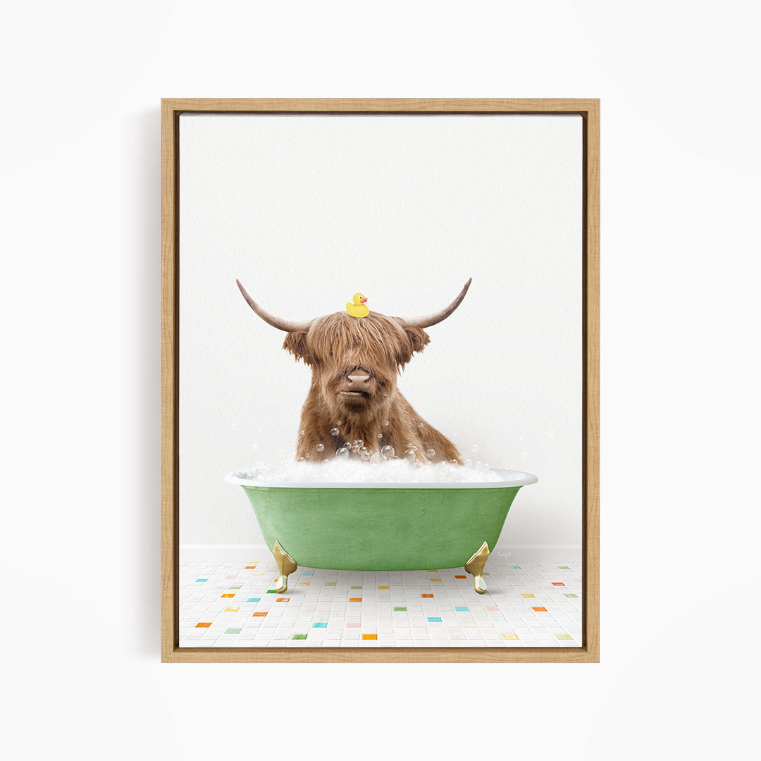 A brown cow with long horns is sitting in a green bathtub filled with bubbles, with a yellow rubber duck perched on its head.