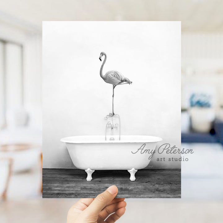 a person holding up a card with a flamingo in a bathtub