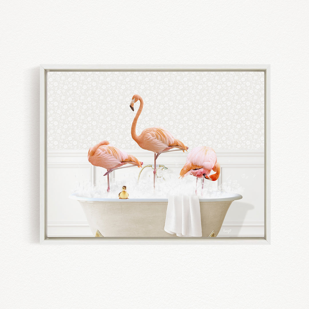 A framed image depicting three pink flamingos standing in a bathtub filled with water and bubbles, with a small yellow duck floating on the water's surface.