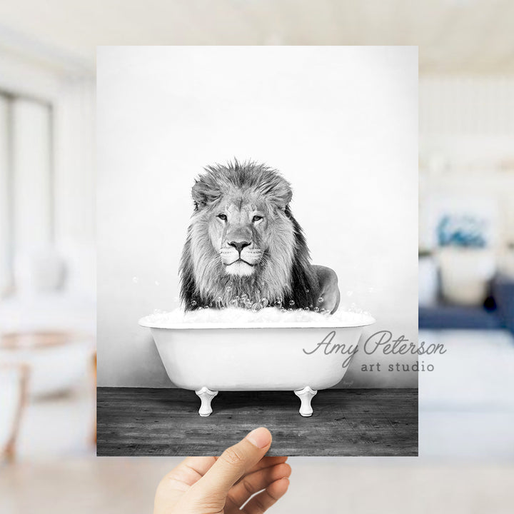 a hand holding up a black and white photo of a lion in a bathtub