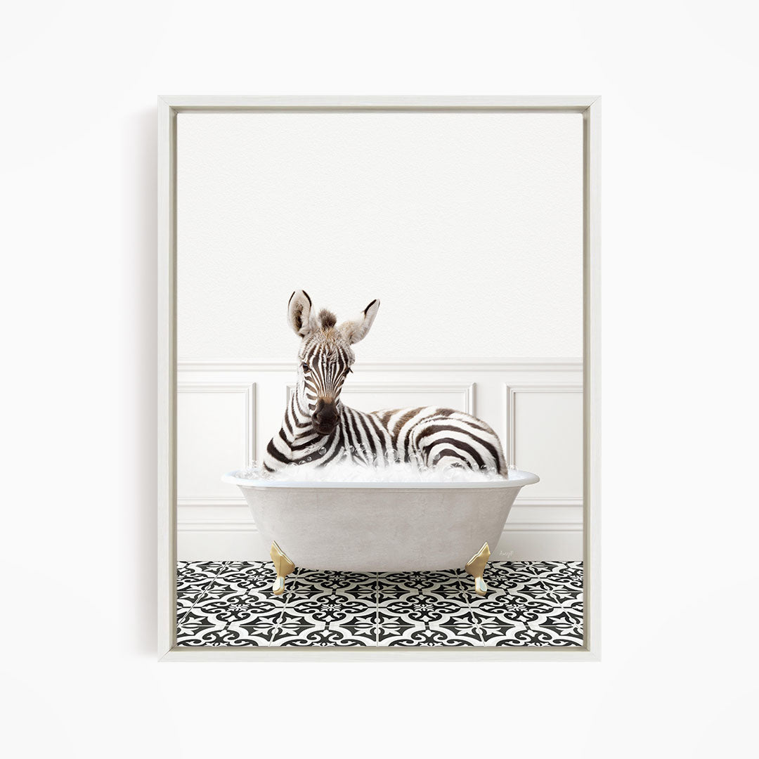 A zebra is sitting in a white bathtub, surrounded by a black and white patterned floor.