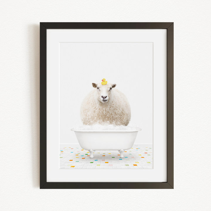 A fluffy white sheep sits in a white bathtub filled with bubbles, with a yellow rubber duck perched on its head.