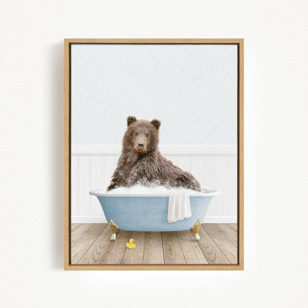 A brown bear sitting in a blue bathtub filled with bubbles, with a yellow rubber duck nearby.