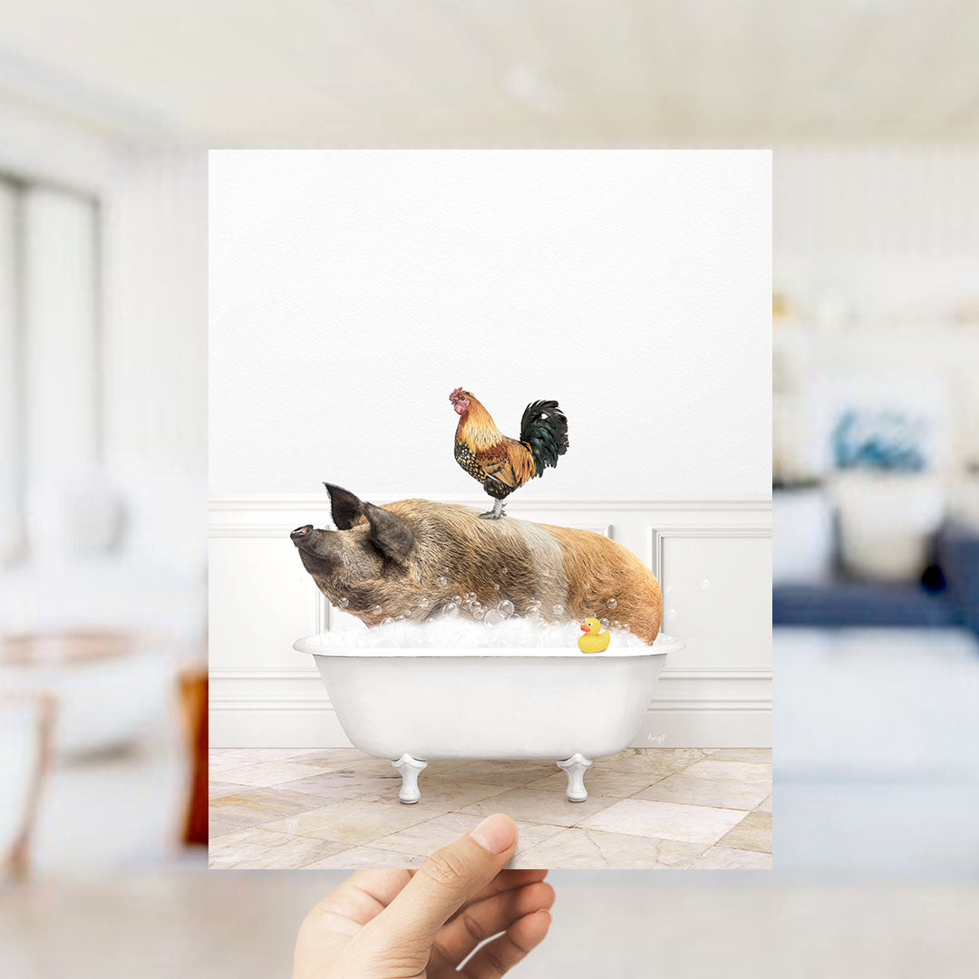 A hand holds up a framed image depicting a pig sitting in a bathtub, with a rooster perched on its back.