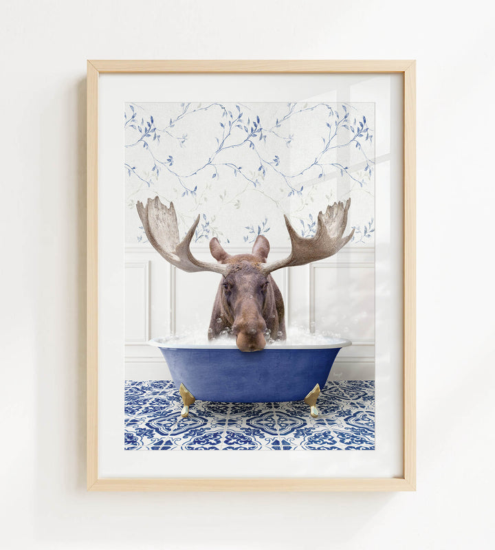 A moose with large antlers is sitting in a blue bathtub, surrounded by a patterned tile floor and a white wall with blue floral wallpaper.