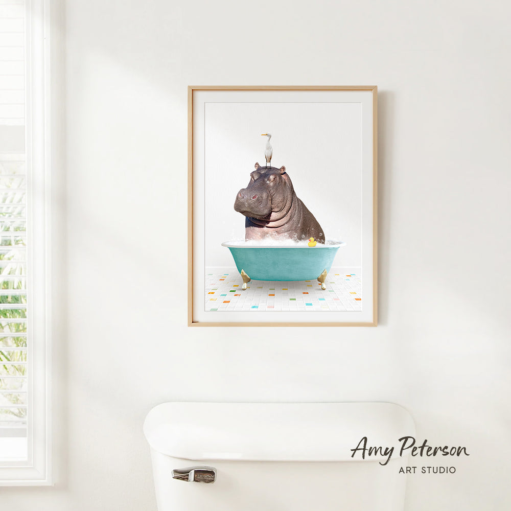 A framed image of a hippopotamus sitting in a bathtub, surrounded by colorful tiles, is displayed on a white wall.