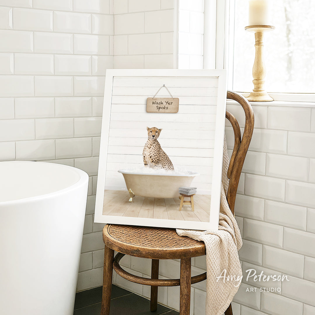 A framed print of a cheetah sitting in a bathtub, with a sign above it that says "Wash Your Spots".