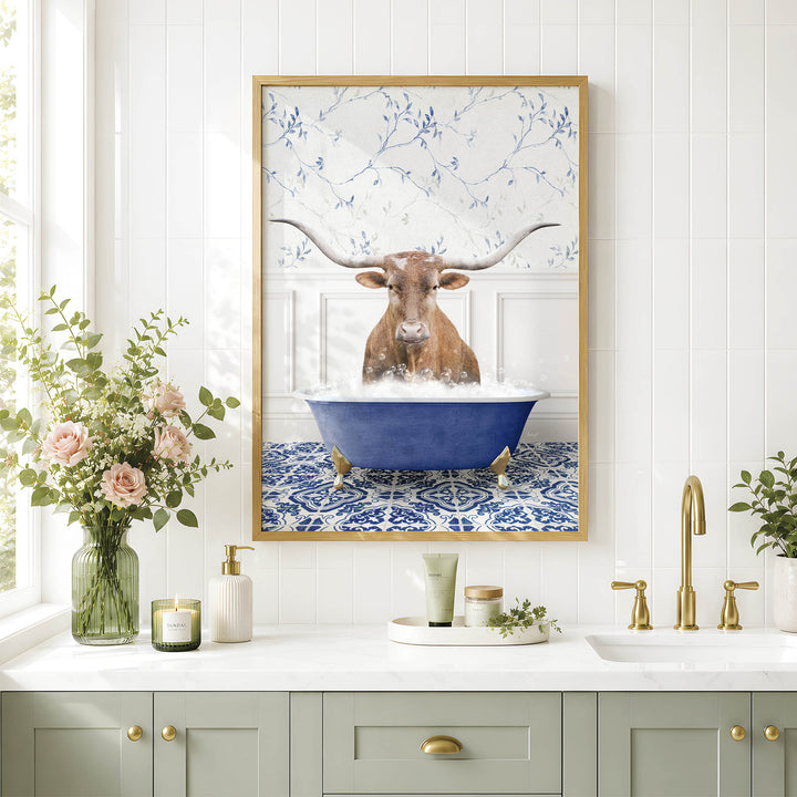 a framed picture of a bull with long horns sitting in a blue bathtub, surrounded by flowers and a white and blue floral pattern on the wall.
