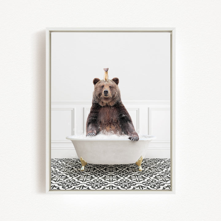 A brown bear sitting in a white bathtub, with a small animal perched on its head.