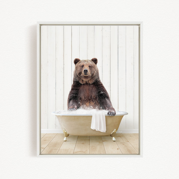 A brown bear sitting in a bathtub filled with water, with a towel draped over the side of the tub.