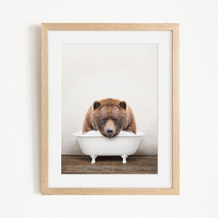 A brown bear is sitting in a white bathtub, appearing to be enjoying a relaxing bath.