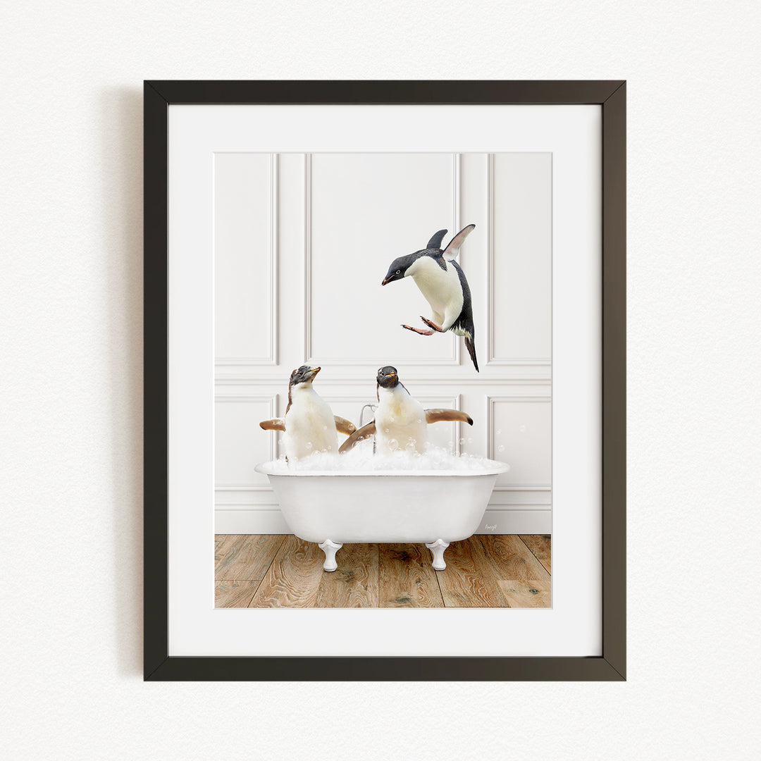 A framed image depicting three penguins sitting in a white bathtub, with one penguin flying towards the others.