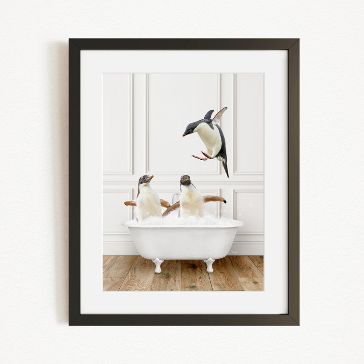 A framed image depicting three penguins sitting in a white bathtub, with one penguin flying towards the others.