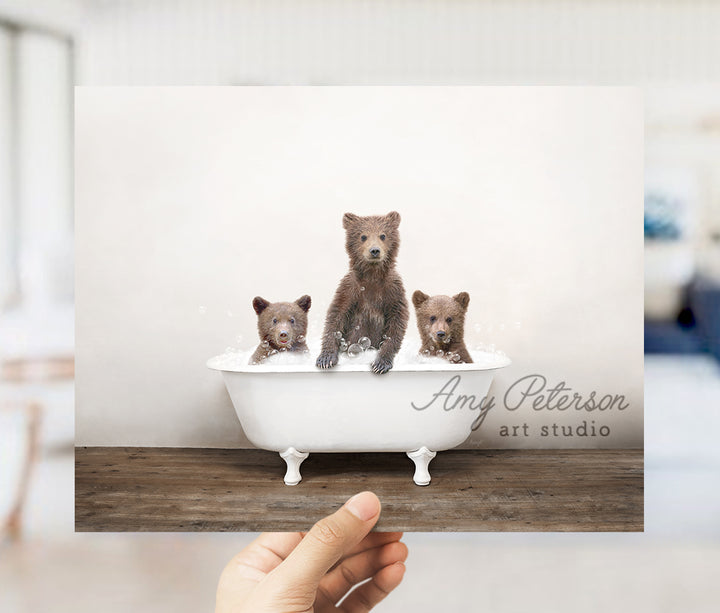 a person holding up a card with three bears in a bathtub