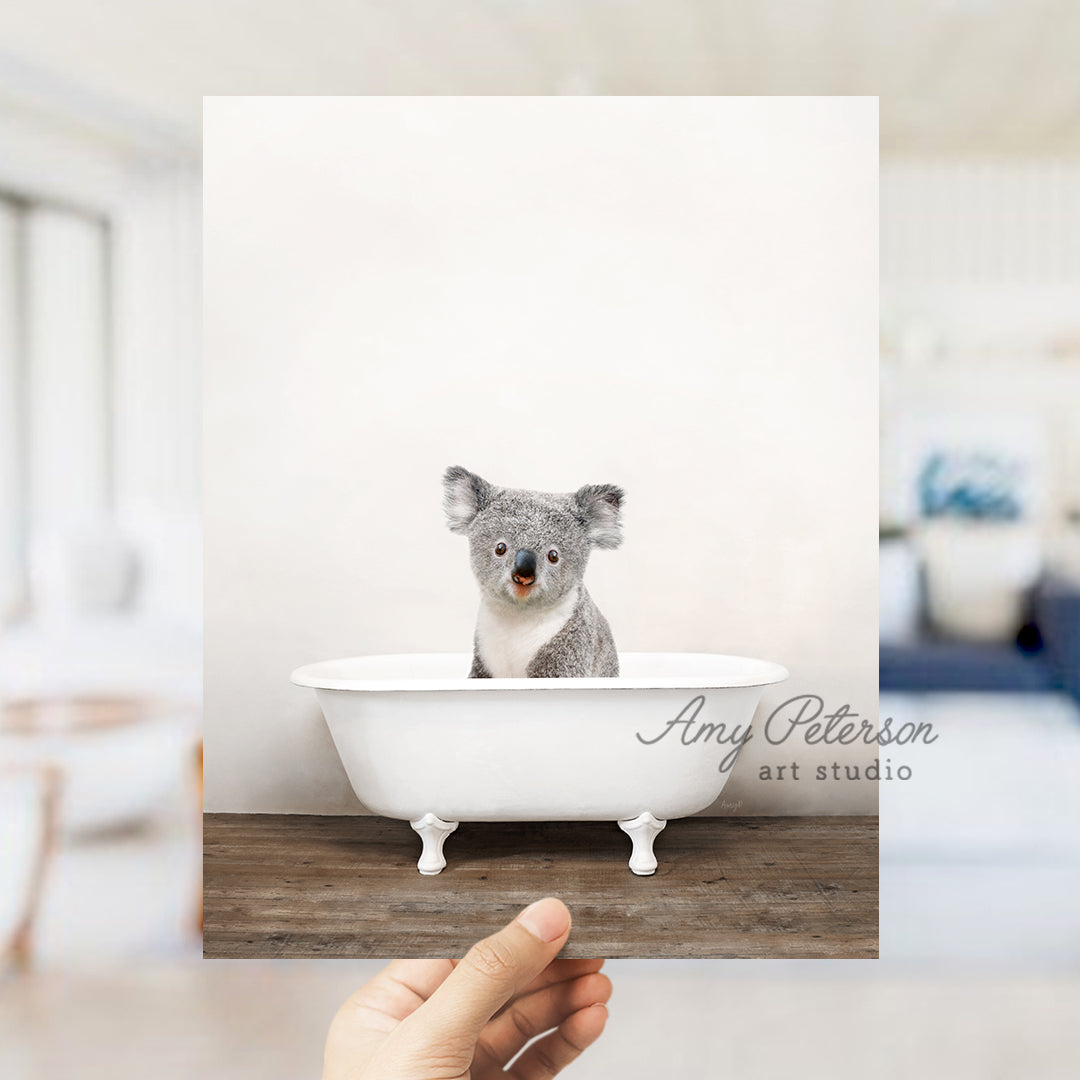 a hand holding a card with a picture of a koala in a bathtub