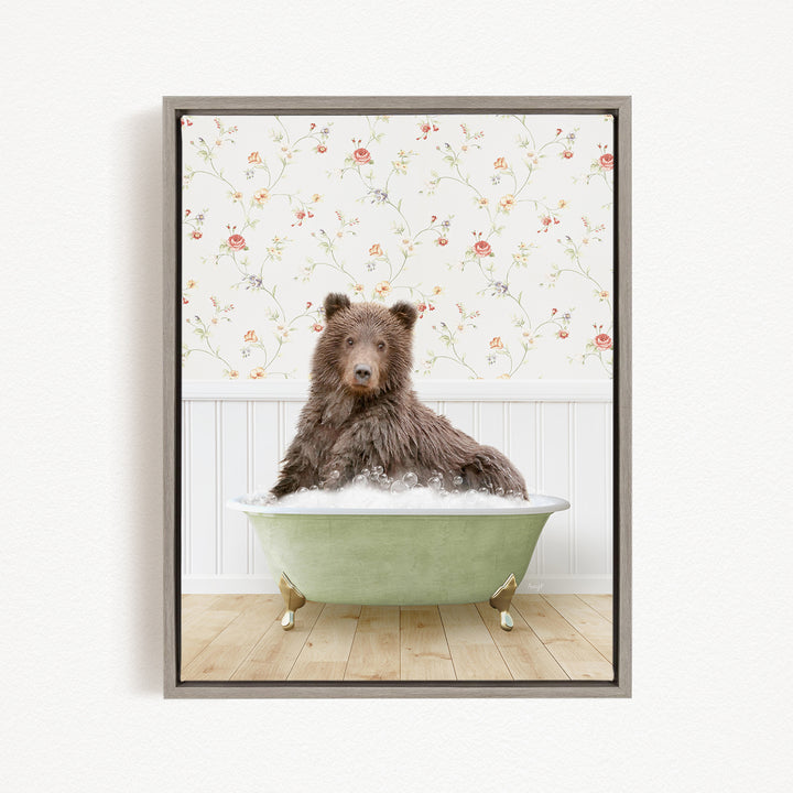 A brown bear sitting in a green bathtub filled with bubbles, with a floral wallpaper in the background.